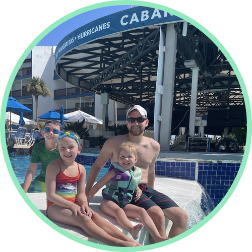 A family of four sitting together in front of a pool.
